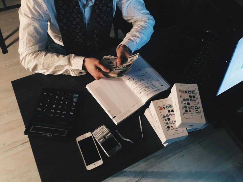Top Bookkeeping Services for Small Businesses 2 Businessman organizing finances with tech devices and cash on desk.